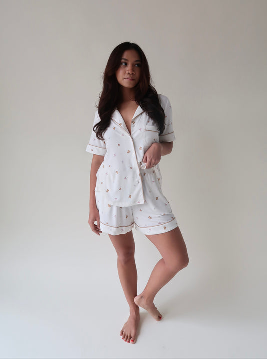 Woman wearing a white pajama set with small patterns on a plain background
