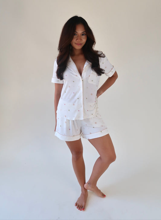 Woman wearing a white pajama set against a plain background